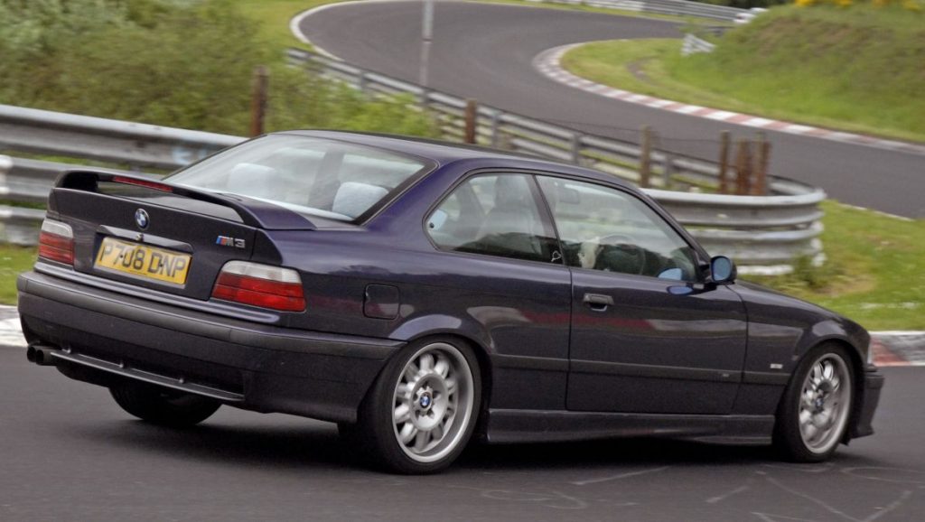 A techno violet BMW E36 M3 Evo being driven heroically well on the Nurburgring.